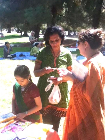 janmastami-ponderosa-park-03 Abha Devi Dasi shares information about our community with a guest while her daughter Lavanika organizes the book table